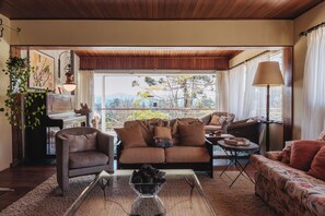 A cozy living room with a sofa, chairs, a coffee table, and a piano. - Refúgio Ultramor: sua casa na montanha (Campos do Jordão)