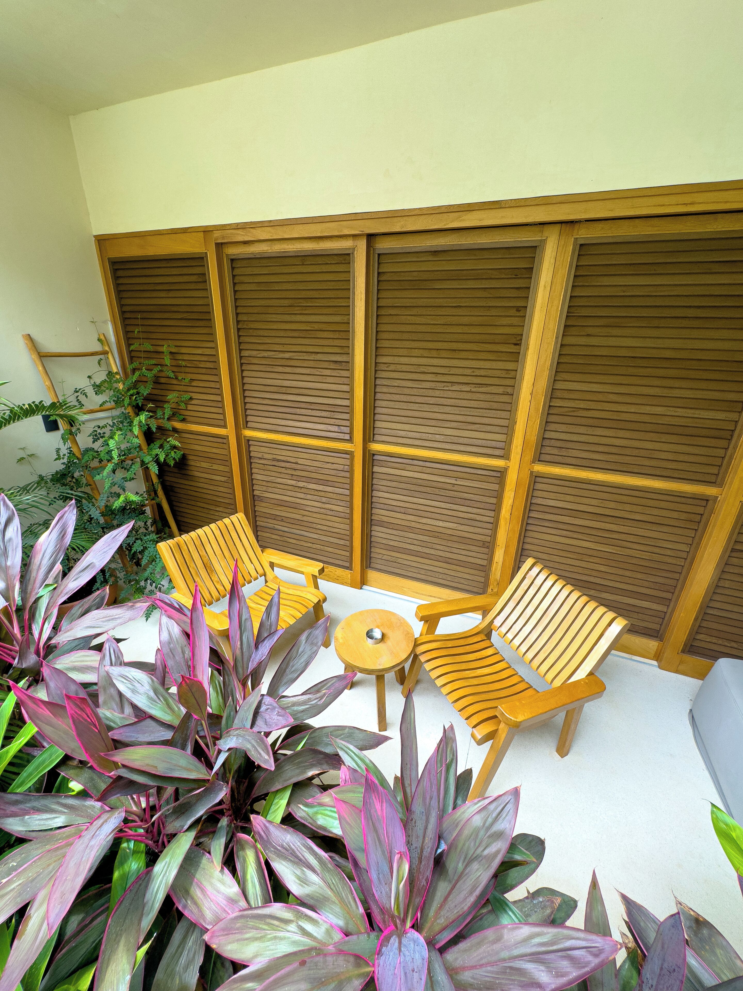 Un espace extérieur aménagé avec du mobilier en bois, comprenant des chaises et une petite table ronde.