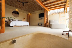 A spacious bedroom with a large bed, a white armchair, a small table, and a TV on the wall. - Casa Borka LUXURY FULLY FURNISHED BEACH CONDOS WITH POOL (Puerto Escondido)