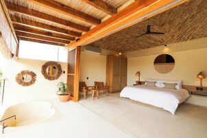 Un dormitorio amplio con una cama grande, ventilador de techo y vistas al exterior.