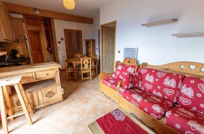 Una sala acogedora con un sofá de madera, una mesa de comedor y una cocina con armarios de madera y una estufa.