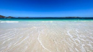 Ein Strand mit klarem türkisblauem Wasser und weißem Sand.