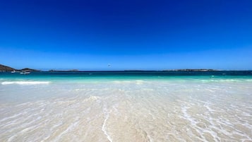 A beach with clear turquoise water and white sand.