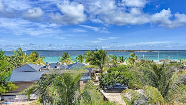 Ein Küsteneigentum mit Blick auf das Meer, Palmen und einen klaren Himmel.