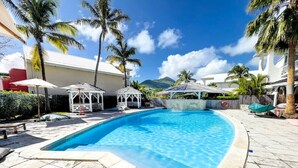 Ein Pool mit gefliestem Deck, Palmen und blauem Himmel.