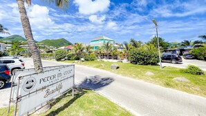 A beachside road with a sign for 'Peter McCoole Irish Pub' and a building in the background. - La Plage 37 – Sea View, Pool & Steps from the Beach (Orient Bay)