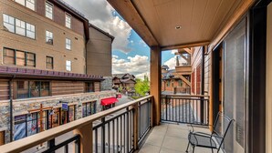 Ein Balkon mit Blick auf eine Straße, ein Steinhaus und ein rotes Markisen