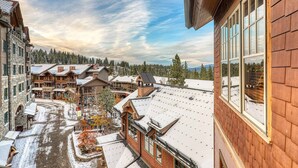 A snow-covered building with large windows and a view of a town square with other buildings and a snow-covered street. - Catamount Lodge 404 Two Bedroom (Truckee)