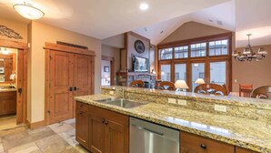 A spacious kitchen with granite countertops, wooden cabinets, and a built-in dishwasher. - Catamount Lodge 404 Two Bedroom (Truckee)