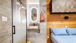A modern bathroom with a glass shower enclosure, a wooden vanity, and a mirror.