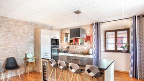 A modern kitchen with a large island, bar stools, and a dining area.