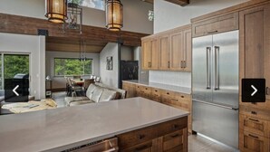 A modern kitchen with wooden cabinets, stainless steel appliances, and a large island. - Ski-in/out Mod/Indust Luxe Schweitzer Mountain (Sandpoint)