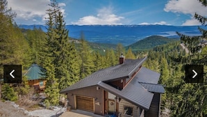 A modern house with a sloped roof, a garage, and a view of mountains and a lake. - Ski-in/out Mod/Indust Luxe Schweitzer Mountain (Sandpoint)