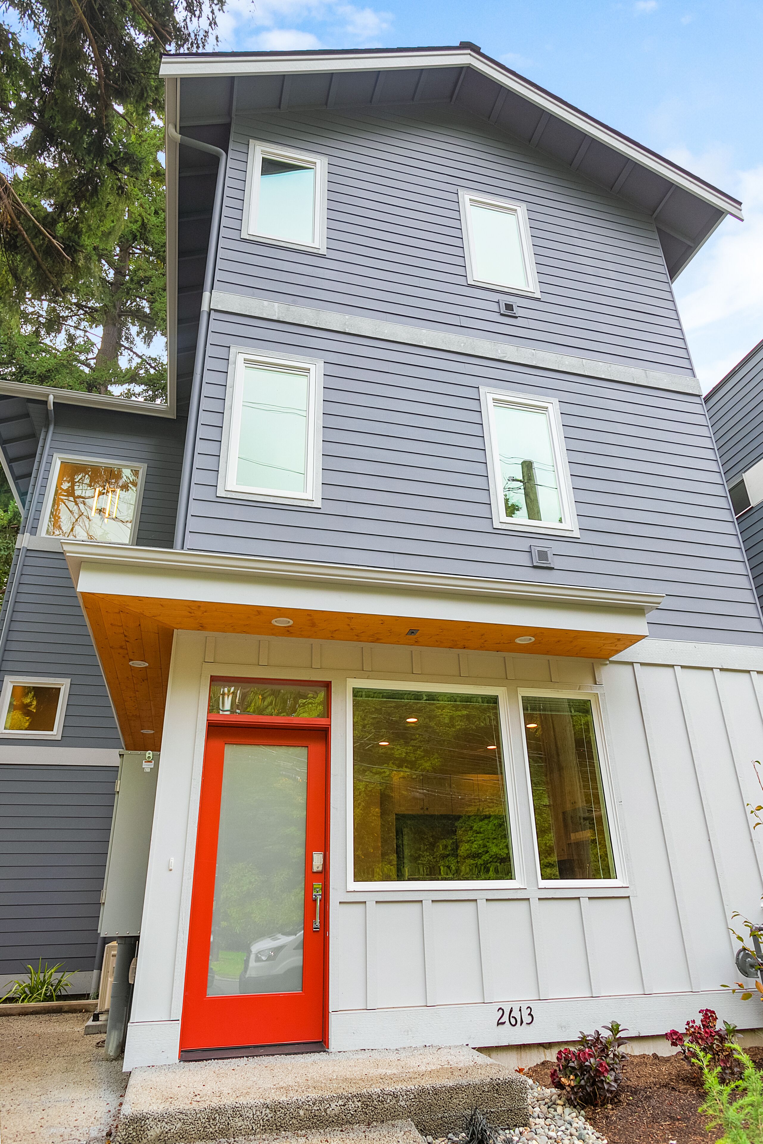 A two-story house with a red door and multiple windows.