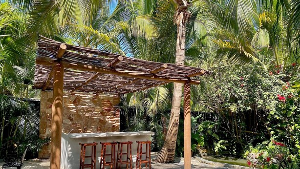 A wooden pergola with a stone wall and a bar area with stools. - Villa Tortolas 5 Min Walk To La Ropa Beach (Zihuatanejo)