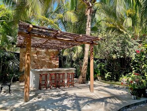 Eine Holzpergola mit einer Steinmauer und einer Bar mit Hockern.