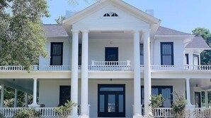 A two-story house with a central entrance, columns, and a balcony on each floor. - Millarden Farms Main House (Woodbury)