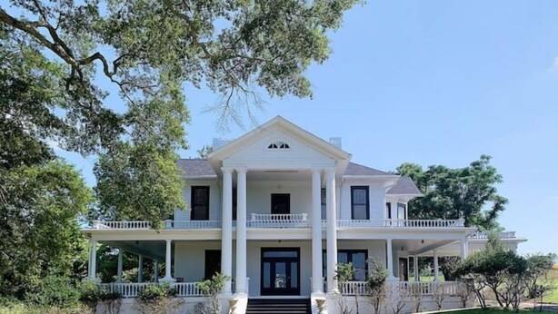 A two-story house with a central entrance, a covered porch on each floor, and a symmetrical facade. - Millarden Farms Main House (Woodbury)