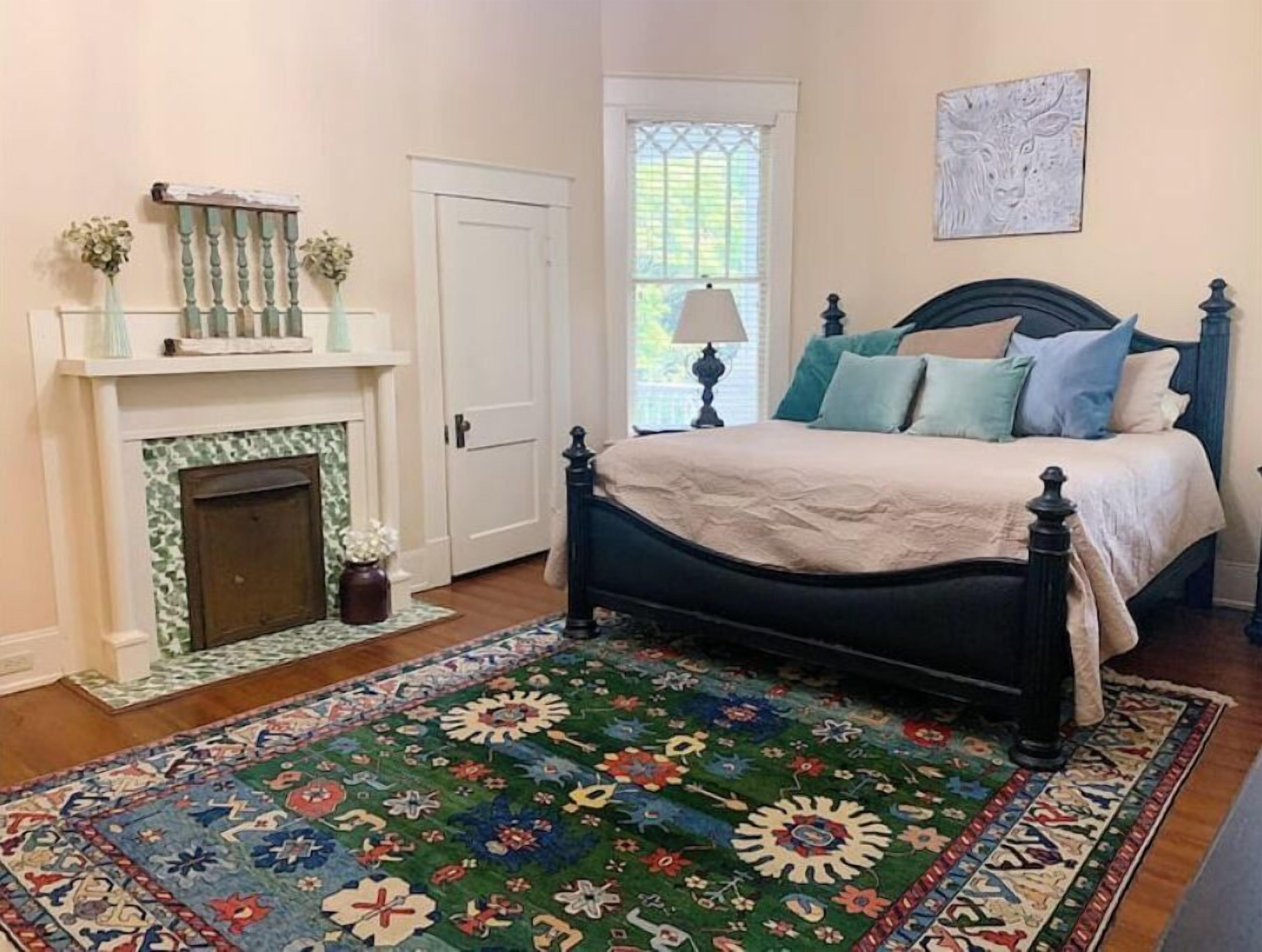 Une chambre à coucher avec un lit, une cheminée, une fenêtre et un tapis.