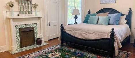 Une chambre à coucher avec un lit, une cheminée, une fenêtre et un tapis.
