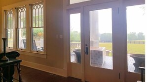 A room with a large window, a door leading outside, and a view of a deck. - Millarden Farms Main House (Woodbury)