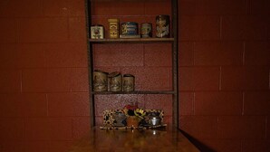 Una mesa de madera con un estante encima, frente a una pared de ladrillo.