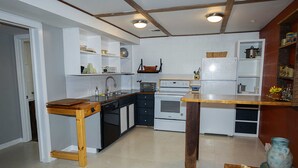 Una cocina con armarios blancos, una mesa de madera y un horno empotrado.
