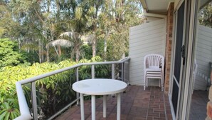 A balcony with a round table and two chairs, surrounded by a metal railing.