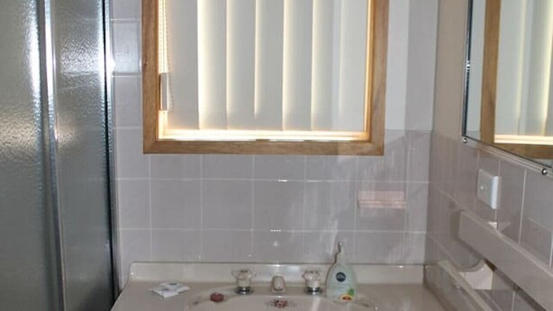 A bathroom with a wooden vanity, a sink, and a mirror.