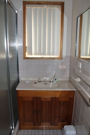 A bathroom with a wooden vanity, a sink, and a mirror.
