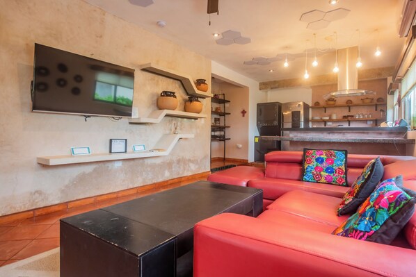 Un salon moderne avec un grand téléviseur à écran plat, un canapé en cuir rouge et une table basse noire.