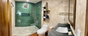 Une salle de bain équipée d’une douche, de toilettes, d’un lavabo et d’étagères où sont rangés les articles de toilette.