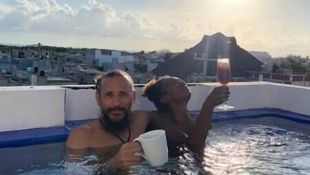 Deux personnes dans un jacuzzi, avec une vue sur la ville et une montagne en arrière-plan.