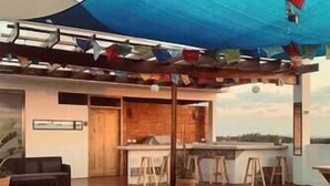 A modern outdoor dining area with a curved ceiling, wooden furniture, and a view of the landscape.