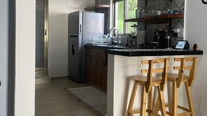 A modern kitchen with a refrigerator, stove, and bar stools.