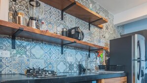 Una cocina con salpicadero decorativo, armarios de madera, horno empotrado, microondas, estufa a gas y refrigerador.