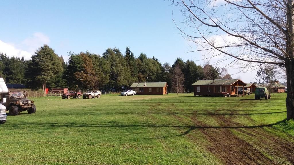 Een grasveld met meerdere gebouwen, waaronder een blokhut en een groter huis.