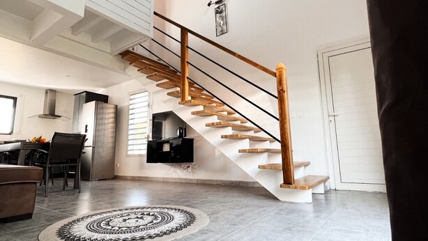 Un amplio espacio habitable con una escalera moderna, un comedor y una cocina.