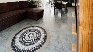 Un amplio salón con un sofá modular, una mesa de comedor con sillas y una alfombra estampada.