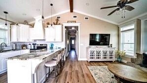 A spacious kitchen with white cabinets, a wooden island, and a dining area with a table and chairs.