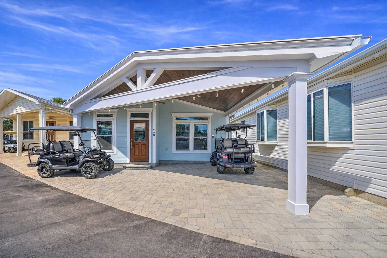 A two-story building with a covered porch, two golf carts, and a paved driveway.