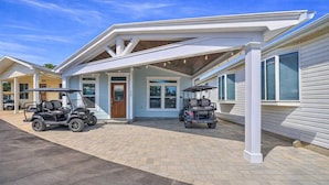 A two-story building with a covered porch, two golf carts, and a paved driveway.