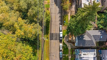 An aerial view of a residential area with houses, a road, and surrounding greenery.