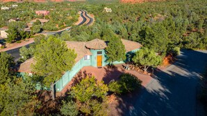 Uma casa com telhado verde e vista para formações rochosas avermelhadas ao fundo.