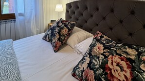 A bedroom with a large bed, floral pillows, a wooden headboard, and framed pictures on the wall. - House of the Apricot trees - independent house/ free parking (Spinea)