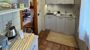 A compact kitchen with white cabinets, a built-in oven, a coffee maker, and a kettle on the counter. - House of the Apricot trees - independent house/ free parking (Spinea)