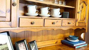 A wooden cabinet with multiple shelves and drawers, containing white ceramic dishes, glasses, and framed photos. - House of the Apricot trees - independent house/ free parking (Spinea)
