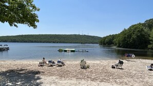 A lakeside beach with lounge chairs and a boat on the water. - Winter fun near Big Boulder Mountain! (Lake Harmony)