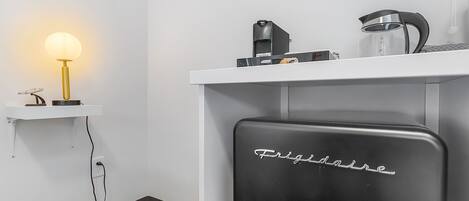 A kitchen with a Frigidaire refrigerator, a coffee maker, and a lamp on a shelf.