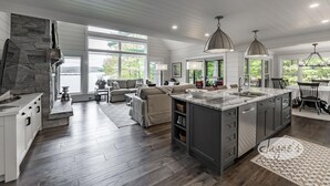 Une cuisine spacieuse dotée d’un grand îlot central, de planchers en bois et d’un mur d’accent en pierre.